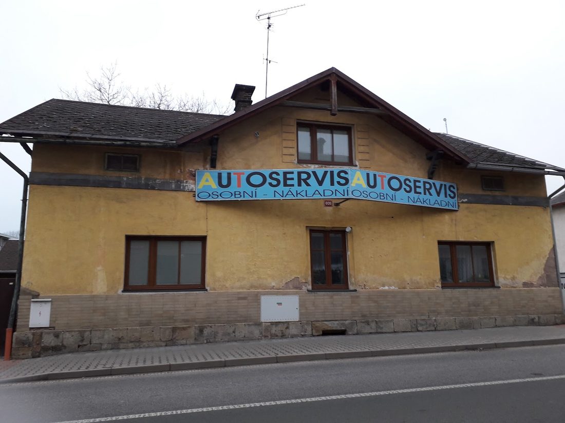 Žlutý dům s modrou cedulí Autoservis, osobní a nákladní